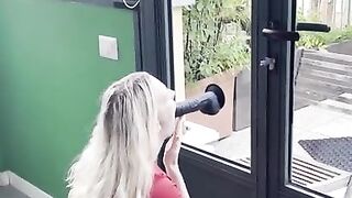 Horny blonde with big tits sucks a suction cup dildo in front of the window