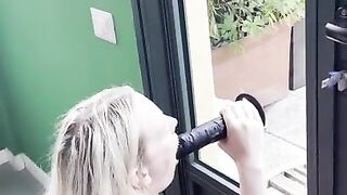 Horny blonde with big tits sucks a suction cup dildo in front of the window