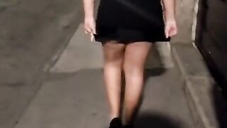 A short girl walking in a dress and showing her thong